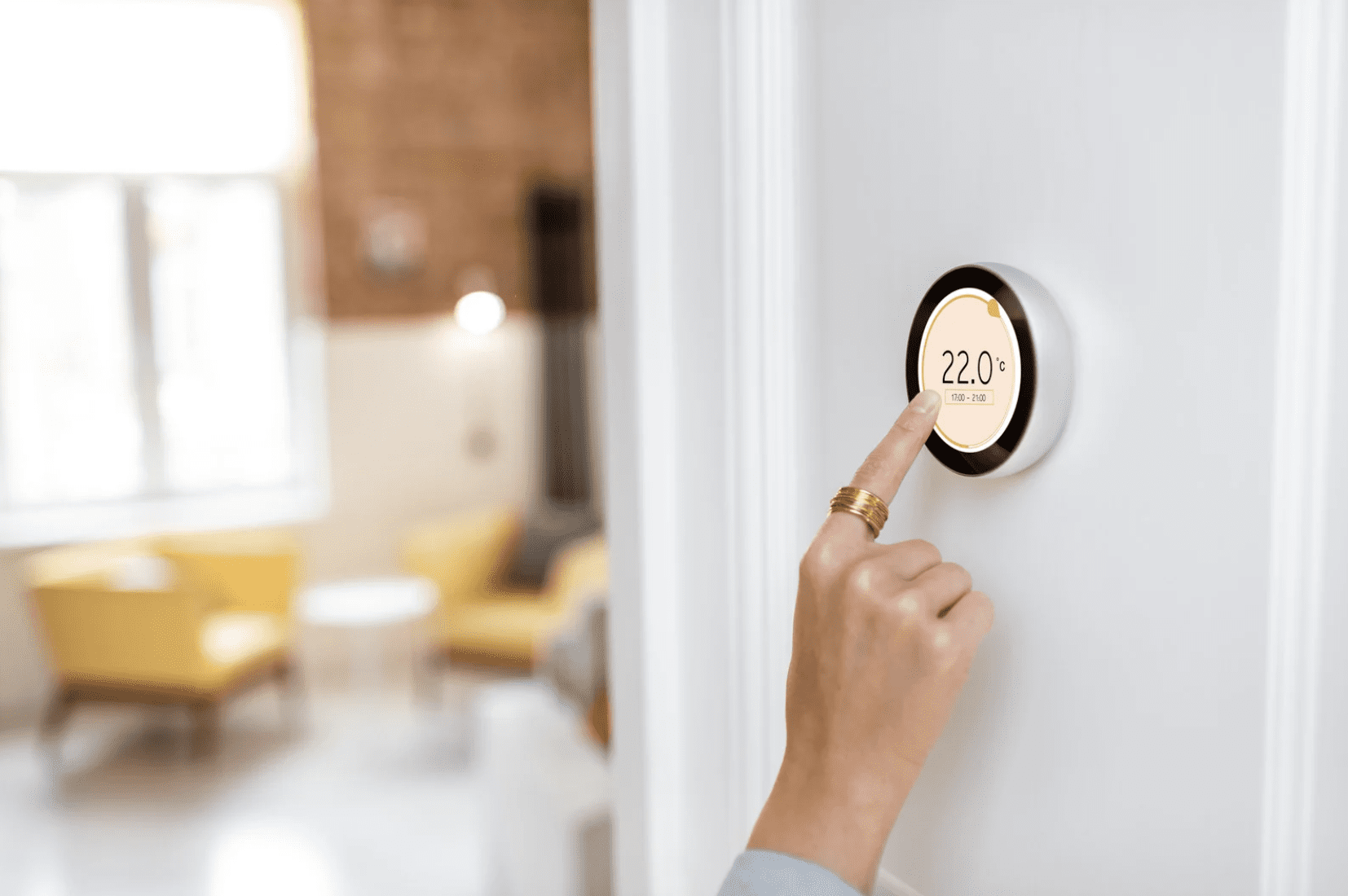 A person with a big gold ring changing the temperature on a smart home thermostat